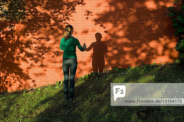 Teenage girl standing by brick wall