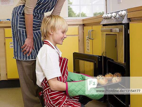 Ein Junge nimmt Brot aus dem Ofen