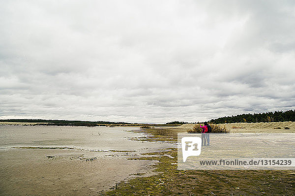 Zwei junge Erwachsene beim Wandern  stehen am See und betrachten die Aussicht