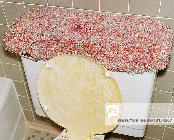 Toilette mit rosa Teppich auf dem Spülkasten