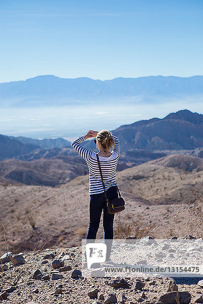 Junge Frau auf Felsen stehend  mit Blick auf die Berge  Rückansicht