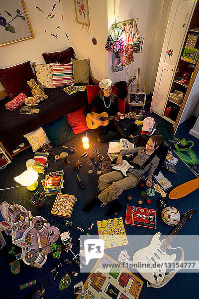 Zwei Mädchen spielen Gitarre in einem überfüllten Raum
