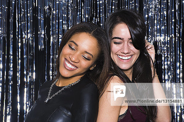 Zwei junge Frauen tanzen Rücken an Rücken in einem Nachtclub
