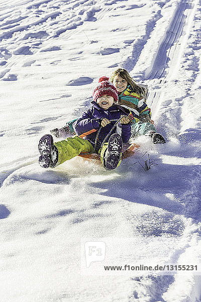 Girls riding sled down snow-covered slope  Achenkirch  Tirol  Austria