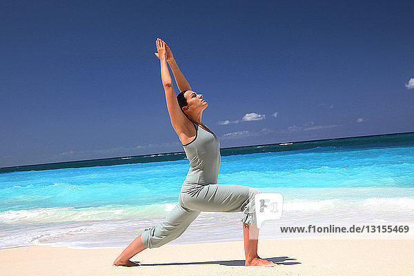Frau übt Yoga am tropischen Strand