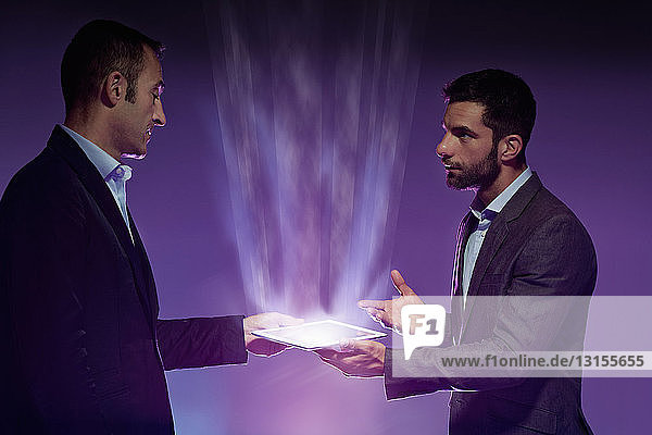 Zwei Männer halten ein digitales Tablet  Licht leuchtet vom Tablet