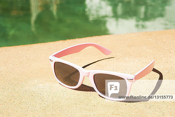 Pair of pink sunglasses on poolside