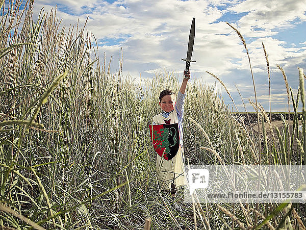 Junge spielt mit Schwert in Weizenfeld
