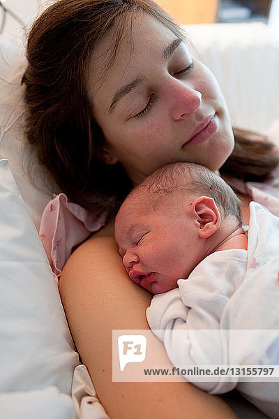Mother and newborn baby boy sleeping in hospital bed