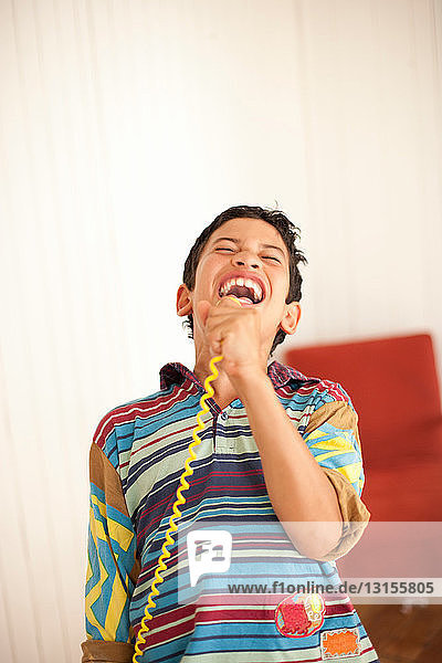 Lächelnder Junge spielt mit Spielzeugmikrofon