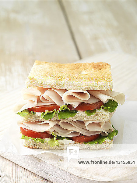 Wafer thin roast chicken with tomato and salad leaves on toasted white sliced bread