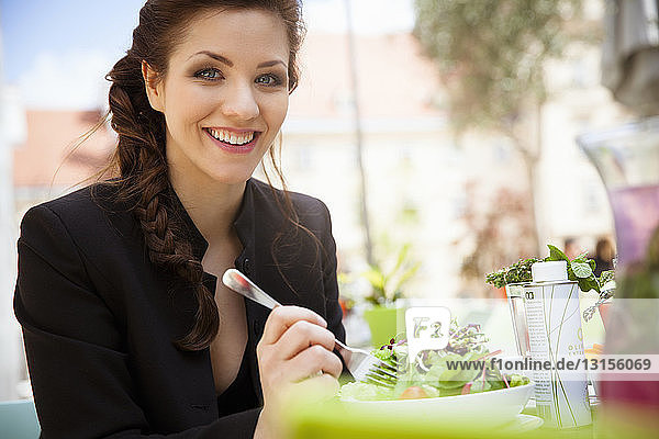 Young adult woman eating salad  outside