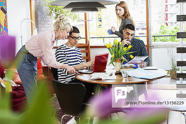 Vier junge Erwachsene sitzen am Tisch und studieren