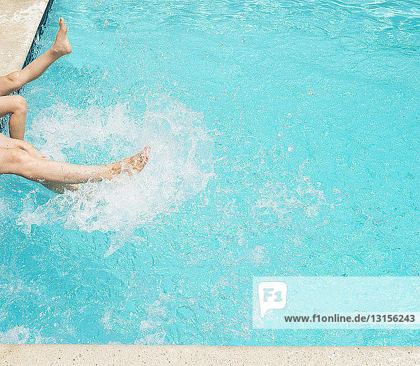 Beine spritzen Wasser im Schwimmbad