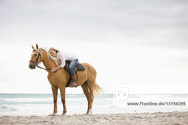 Frau reitet auf einem Pferd am Strand