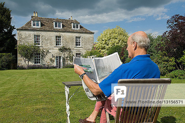 Älterer Mann liest Zeitung im Hinterhof