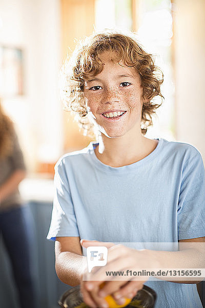 Jugendlicher beim Entsaften von Orangen in der Küche
