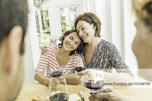 Vier erwachsene Freunde trinken gemeinsam Rotwein am Esstisch
