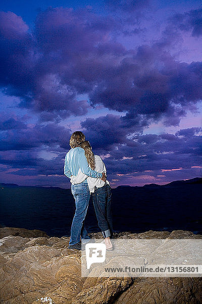 Paar schaut auf einem Felsen in den Himmel