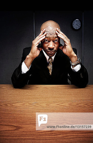 Business man at desk with hands on head
