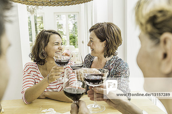 Vier erwachsene Freunde stoßen beim Abendessen mit Rotwein an