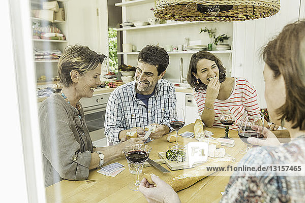 Erwachsene Freunde trinken Rotwein und spielen Karten am Esstisch