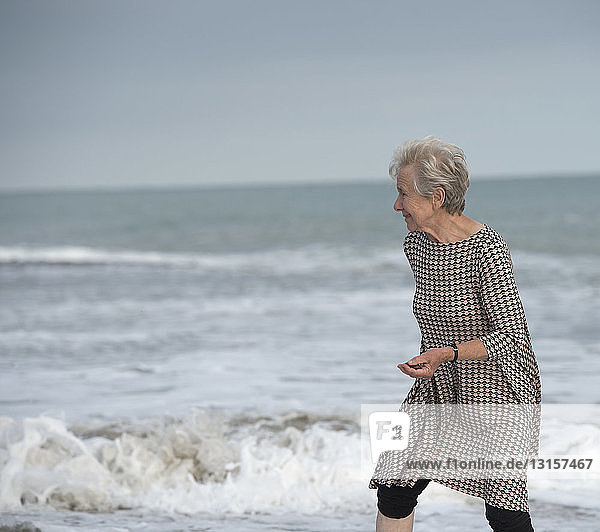 Ältere Frau  die vor den Wellen am Strand wegläuft  Dana Point  Kalifornien  USA