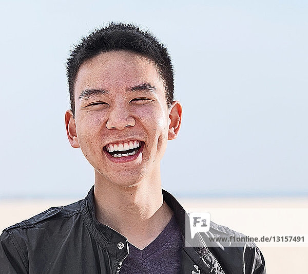 Porträt eines lächelnden jungen Mannes am Strand