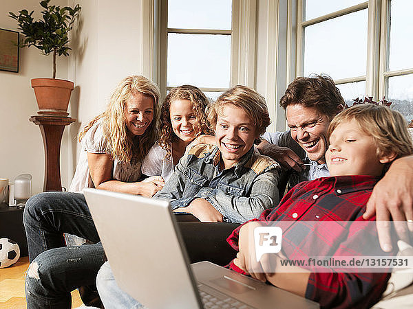 Familie schaut gemeinsam auf dem Sofa Laptop