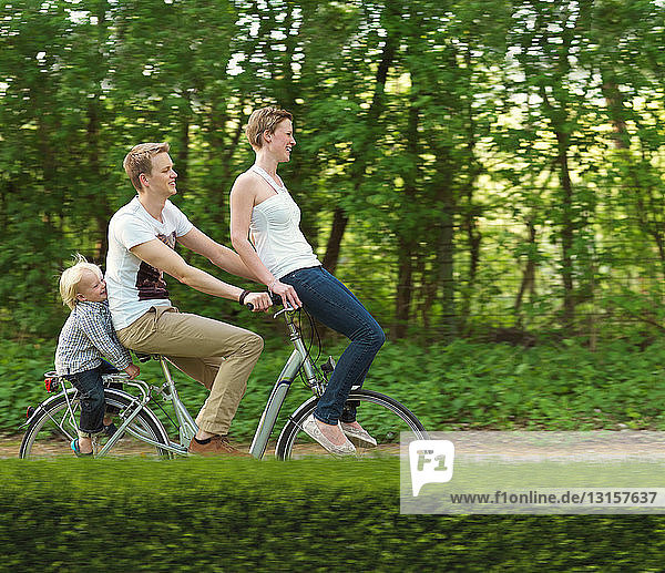 Familie mit einem Kind fährt gemeinsam auf dem Fahrrad