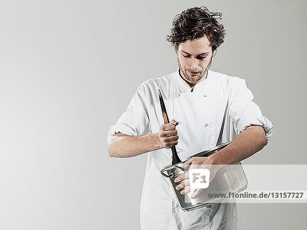 Chef stirring in pan against white background