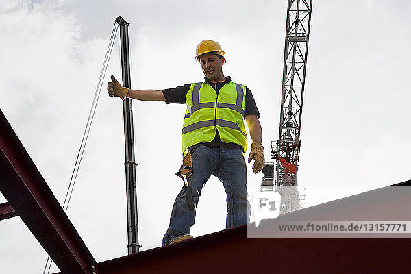 Construction worker guiding crane