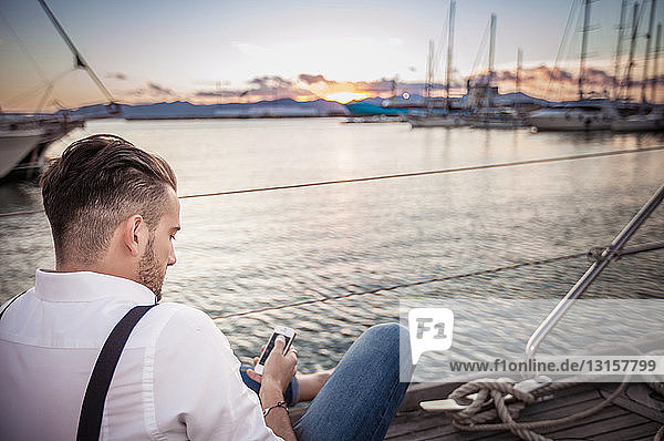 Young man using smartphone on yacht  Cagliari  Sardinia  Italy