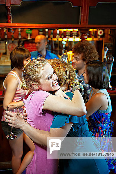 Zwei Mädchen umarmen sich in einer Kneipe/Bar