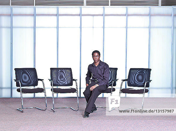 Man sitting on chair in empty office  portrait