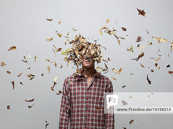 Young man with face obscured by leaves
