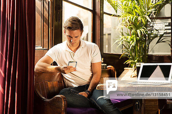 Young man sitting looking at smartphone