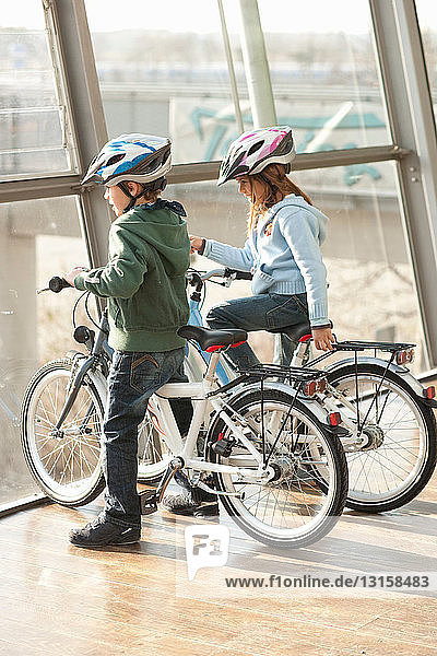 Children sitting on bicycles on bridge