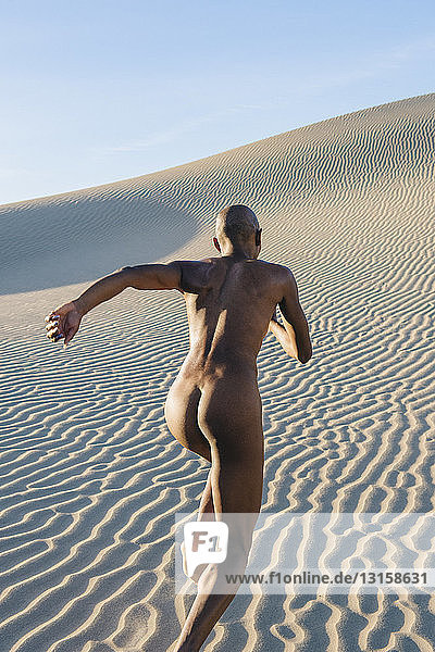 Rear view of nude woman in dessert running