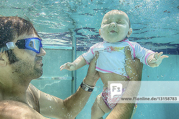 Vater hält seine kleine Tochter unter Wasser
