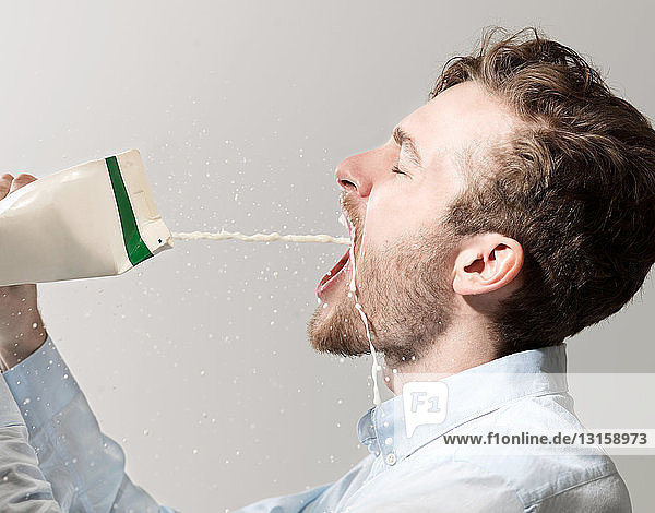 Young man spilling milk from carton  studio shot