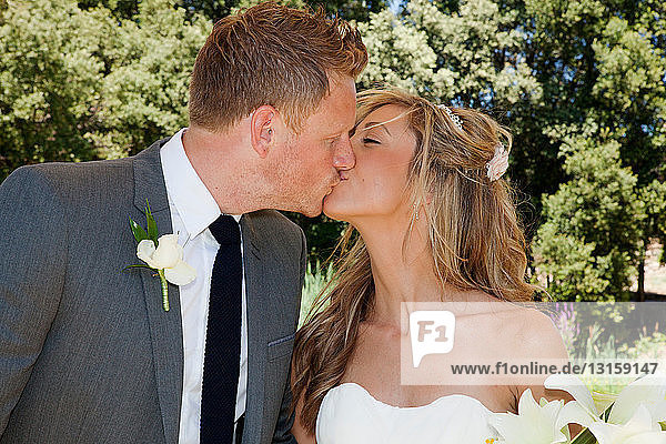 Mid adult bride and groom kissing on wedding day