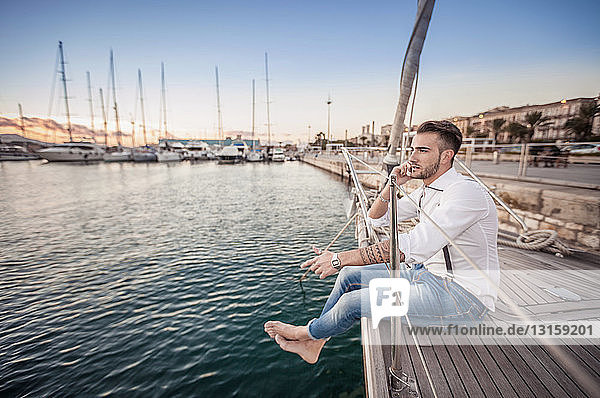 Young man using smartphone on yacht  Cagliari  Sardinia  Italy