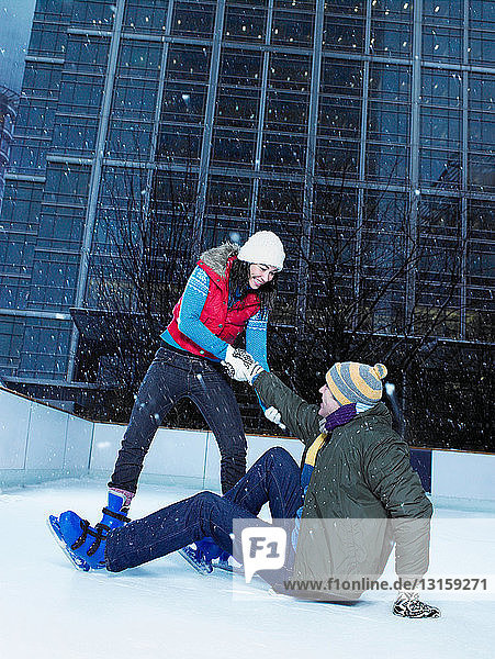 Woman helping man up from ice rink