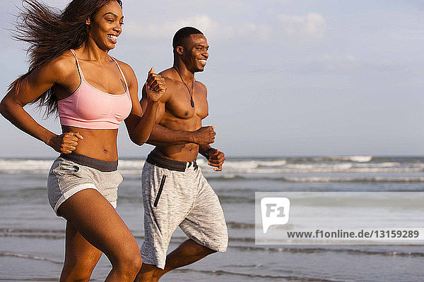Couple running along beach  smiling