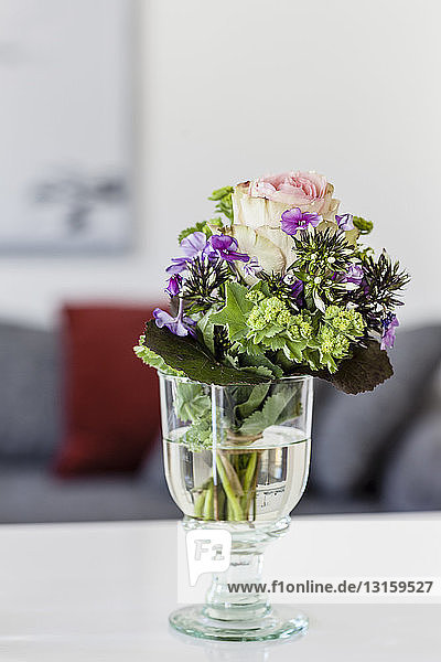 Weinglas mit Schnittblumen auf dem Wohnzimmertisch