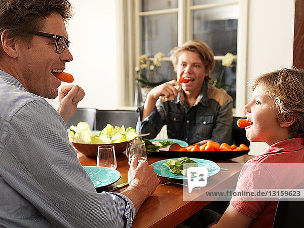 Vater und Söhne sitzen bei einer gesunden Mahlzeit am Tisch