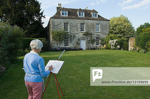 Ältere Frau skizziert Landhaus