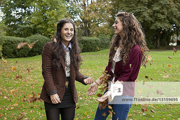 Lächelnde Mädchen spielen im Herbstlaub