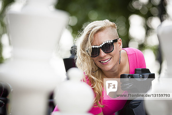 Portrait of mid adult woman with shaved blond hair next to park chess pieces